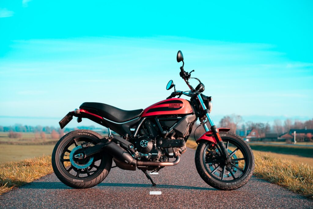 jane-duursma-BPiIiRIhzqI-unsplash - MOTOFLIP Red and black motor bike positioned perpendicular to the road